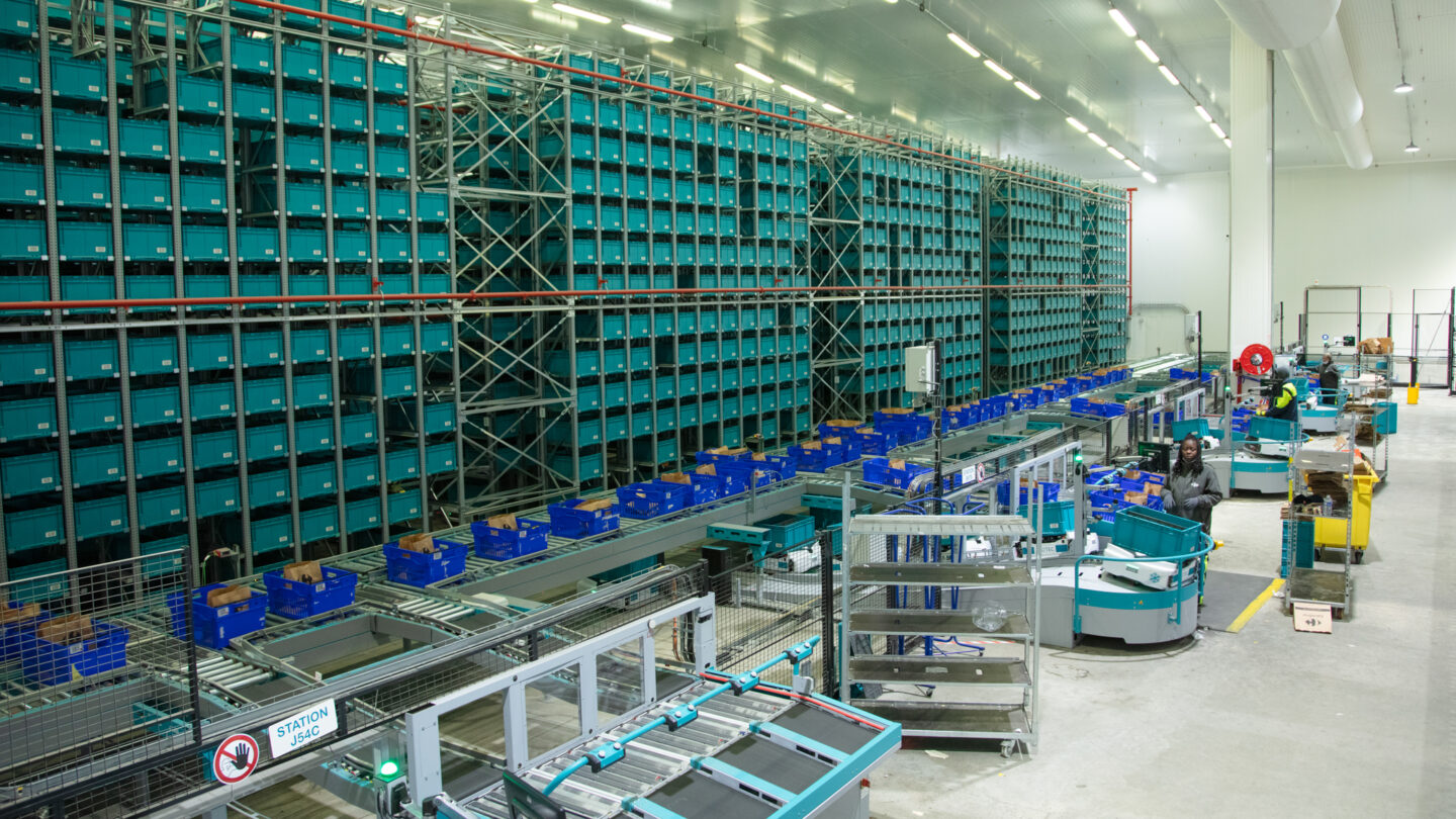 A warehouse with a lot of shelves and supply chain automation machines.