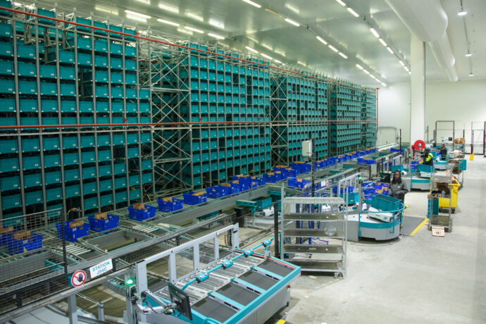 A warehouse with a lot of shelves and supply chain automation machines.