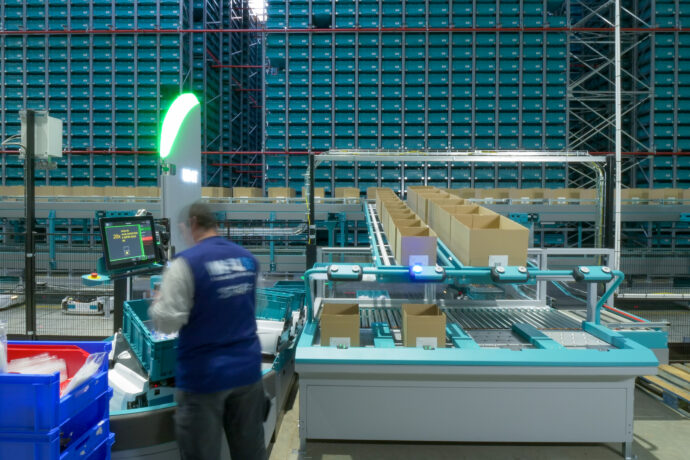 A worker is standing in front of ecommerce warehouse automation system.