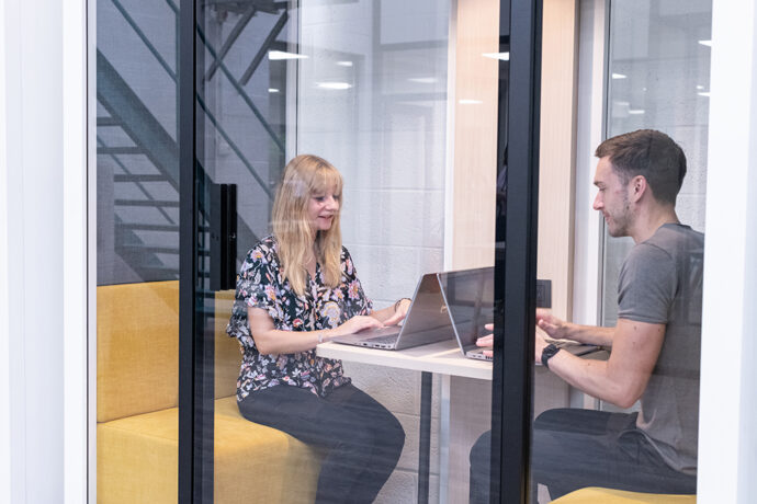 Exotec's employees sitting at a table with laptops in front of a glass door.