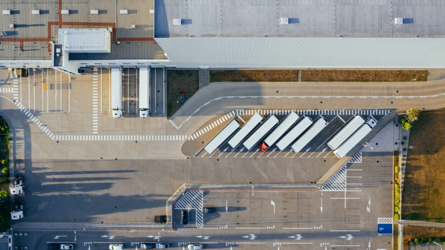 An aerial view of a warehouse and a parking lot in front of it.