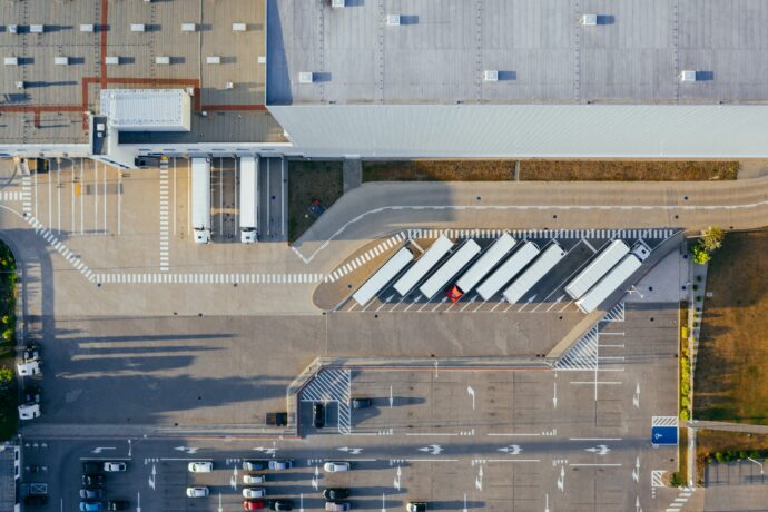 An aerial view of a warehouse and a parking lot in front of it.