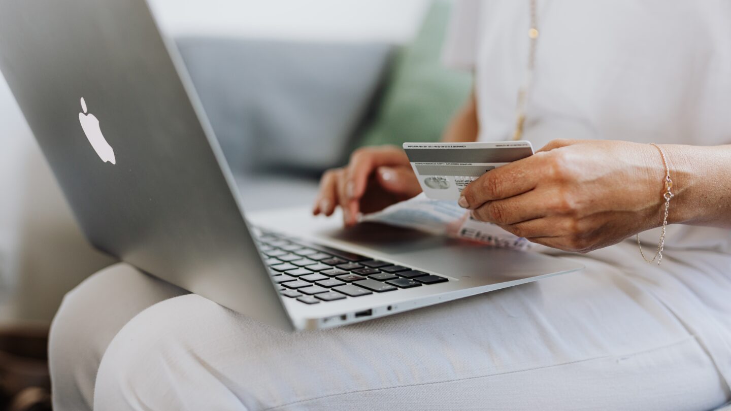 A woman holding a credit card and a laptop.
