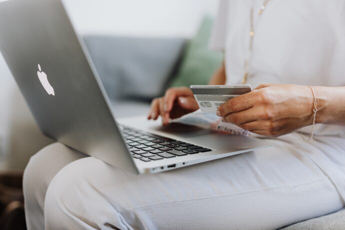 A woman holding a credit card and a laptop.