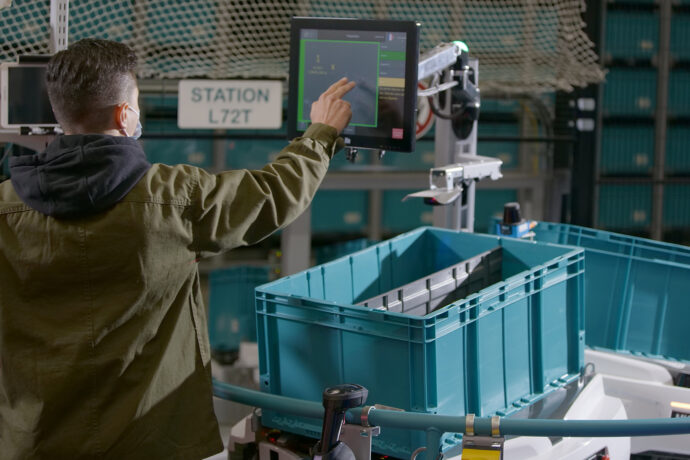A man operating an automated warehouse picking system.