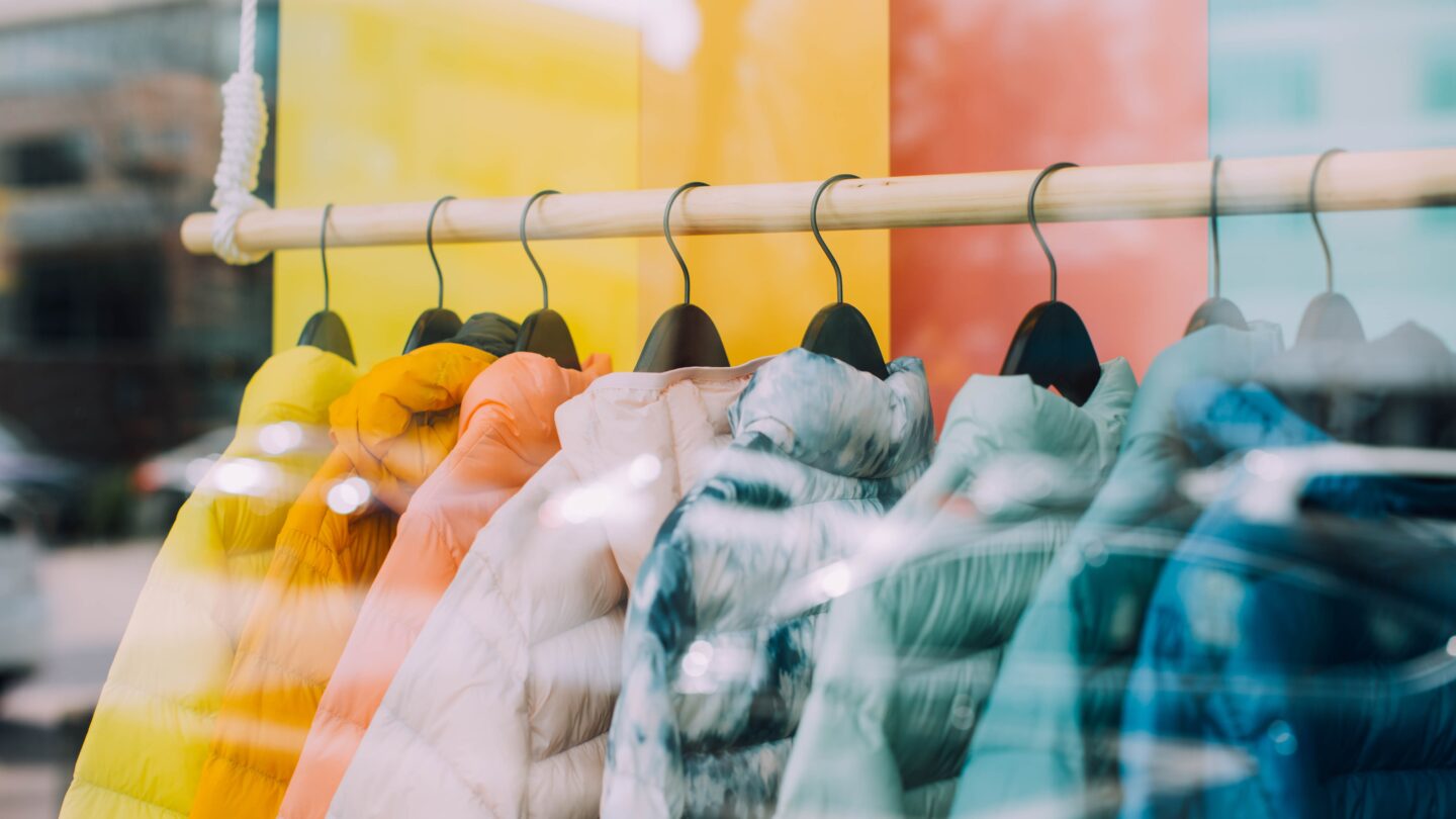 Colorful jackets hanging on a rack in front of a window.