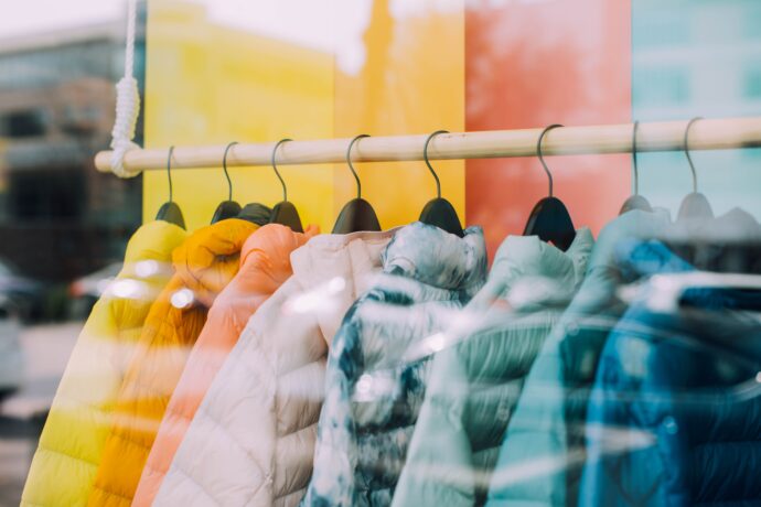 Colorful jackets hanging on a rack in front of a window.