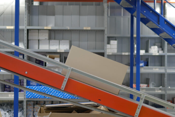 A cardboard box on an industrial conveyor system in a warehouse.