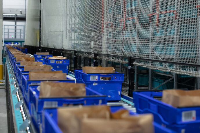 A line of blue boxes on a conveyor belt in a warehouse.