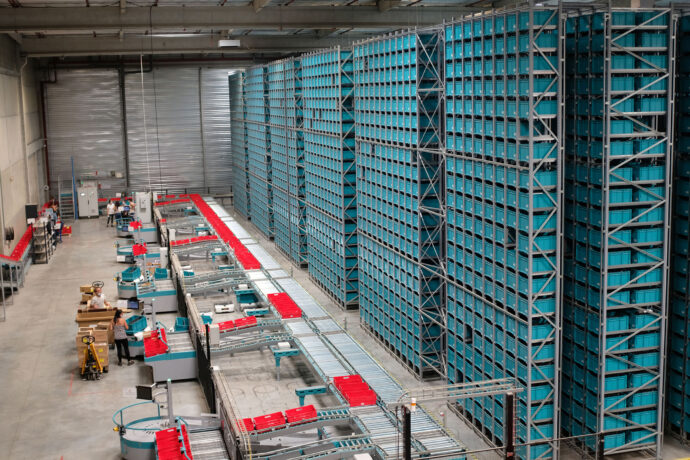 A large warehouse with a lot of shelves and warehouse automation solutions.