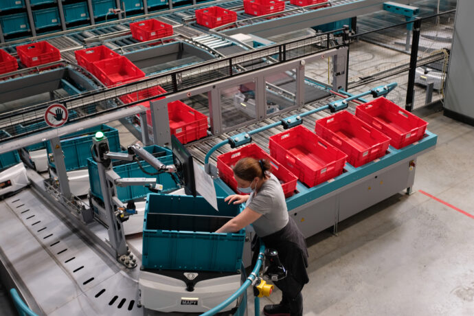 A woman working on an automated conveyor belt in an e-Commerce warehouse.