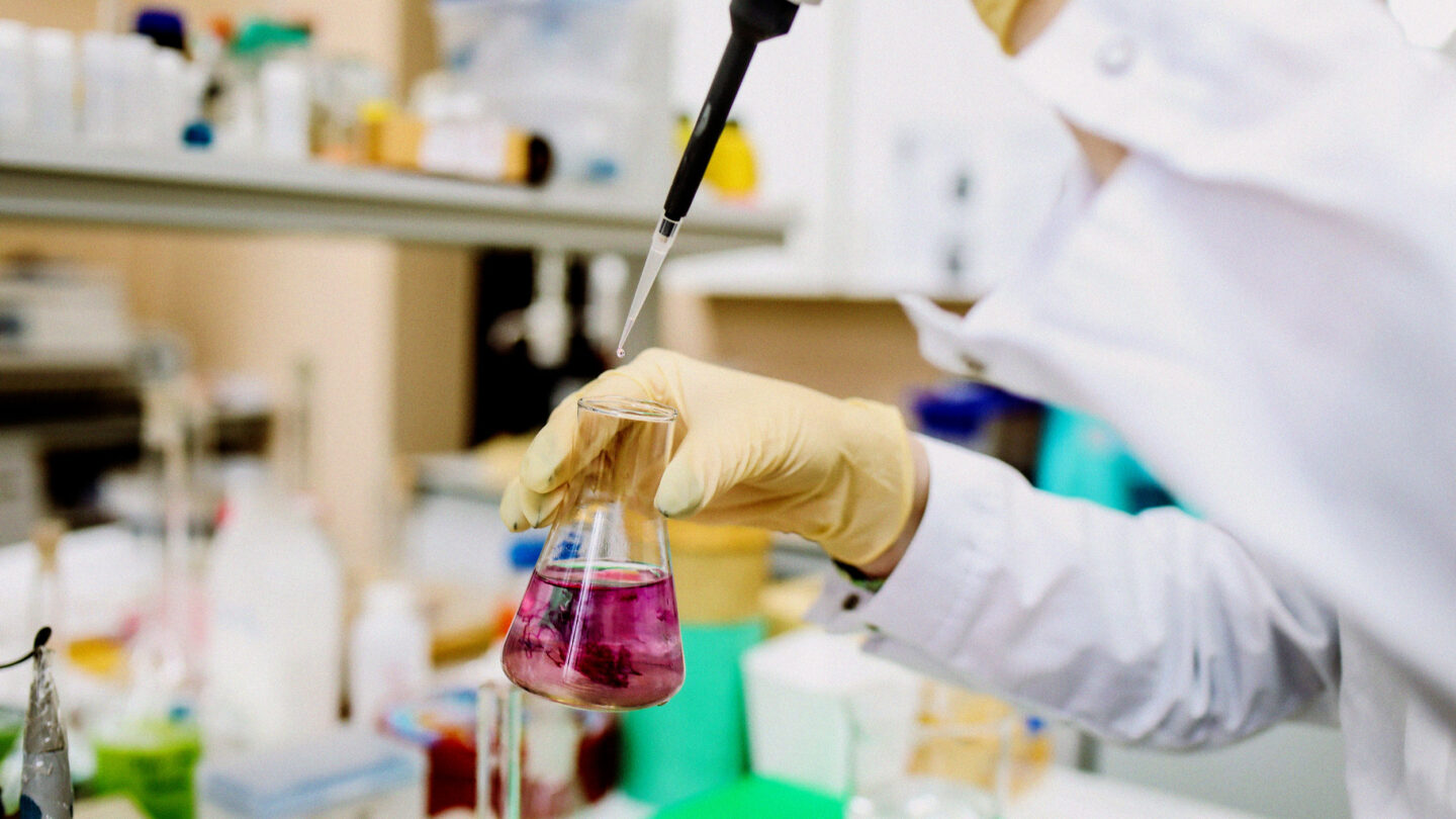 A scientist working in a laboratory with a flask.