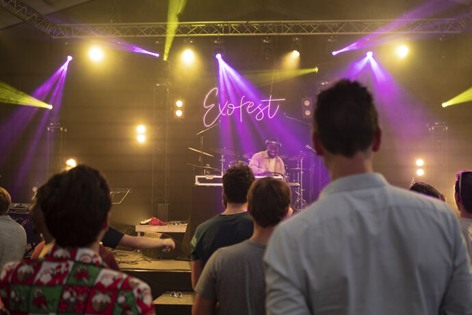 A crowd of people watching a band perform at an Exofest concert.