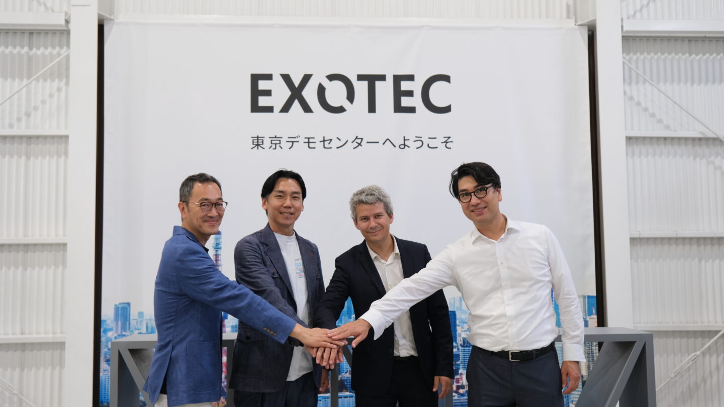 Four menjoin hands in front of an Exotec sign.
