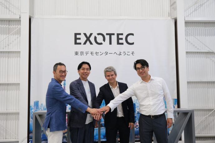 Four menjoin hands in front of an Exotec sign.