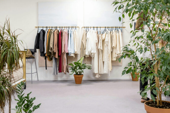 Bunte Kleider und Oberteile an einer Kleiderstange in einem Einzelhandelsgeschäft für Mode.